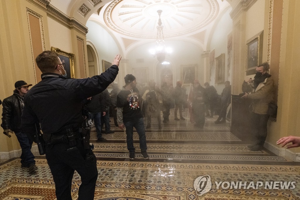 (워싱턴 AP=연합뉴스) 6일(현지시간) 미국 워싱턴DC 연방의회 의사당의 상원 회의장 밖 복도가 흰 연기로 가득 찬 가운데 도널드 트럼프 대통령 지지자들이 의회 경찰과 대치하고 있다. 상ㆍ하원은 이날 합동회의를 개최해 조 바이든 대통령 당선인의 승리를 인증할 예정이었으나 시위대가 의사당에 난입하는 초유의 사태로 회의가 전격 중단됐다.