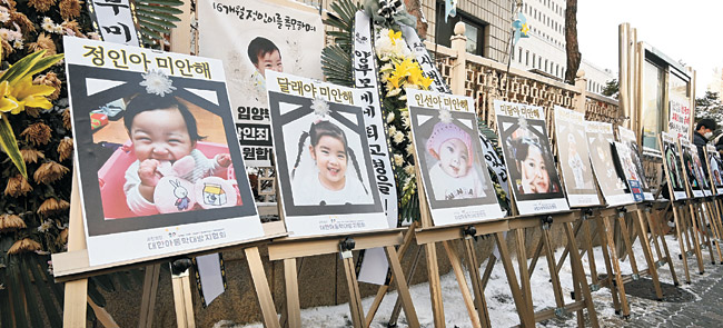 16개월 된 입양아 ‘정인이’를 학대해 숨지게 한 혐의로 기소된 양부모의 첫 공판이 열린 13일 서울 양천구 서울남부지법 앞에 정인이를 비롯해 학대로 사망한 아동들을 추모하는 사진과 조화가 나열돼 있다.  김동훈 기자