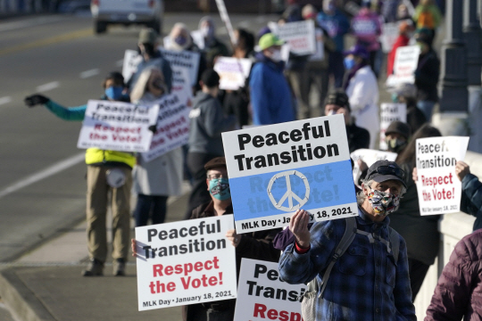 18일 미국 워싱턴주 올림피아에서 평화적 정권교체를 지지하는 시민들이 ‘투표를 존중하라’는 문구가 적힌 플래카드를 들고 가두시위에 나서고 있다.  AP 연합뉴스