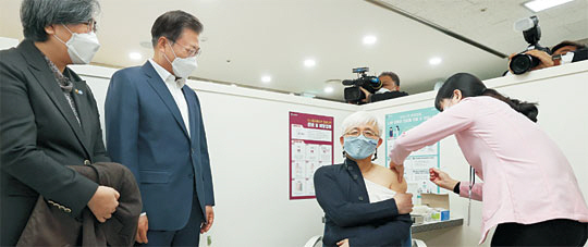 문재인 대통령이 26일 서울 마포구보건소를 방문해 김윤태 푸르메넥슨어린이재활병원 의사가 아스트라제네카 백신을 접종받는 모습을 지켜보고 있다.  연합뉴스