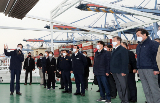 문재인 대통령이 25일 부산신항 한나라호 선상에서 김경수(왼쪽) 경남지사로부터 동북아 스마트물류 플랫폼 구축 등 경제공동체 방안을 포함한 ‘동남권 메가시티 비전’ 보고를 받고 있다. 오른쪽은 이낙연 더불어민주당 대표. 연합뉴스