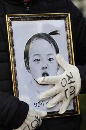 3일 오전 양부모 학대로 숨진 ‘정인이 사건’ 3차 공판이 열린 서울 양천구 남부지방법원 앞에서 한 시민이 정인이 얼굴이 그려진 액자 그림을 어루만지고 있다. 연합뉴스