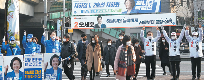 4·7 재·보궐선거 공식 선거운동이 시작된 25일 오전 서울 영등포구 당산역 앞 거리에서 선거운동원들이 선거현수막 아래에서 지지를 호소하고 있다.