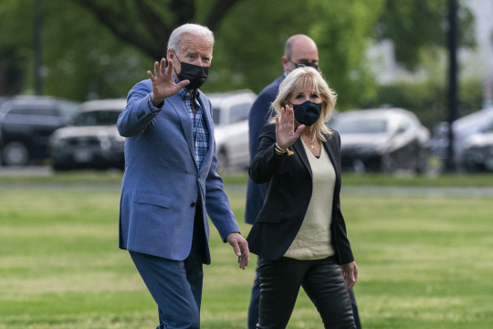 주말을 상원의원 지역구였던 델라웨어주 윌밍턴에서 보낸 조 바이든(왼쪽) 미국 대통령이 25일 워싱턴 DC로 복귀해 백악관으로 걸어가면서 부인 질 여사와 함께 취재진에게 손을 흔들고 있다.  AP 뉴시스