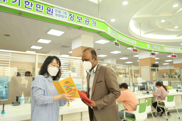 서울 구로구청 직원(왼쪽)이 전입 외국인에게 환영 꾸러미를 전달하며 내용을 설명하고 있다. 구로구청 제공
