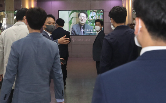 고위공직자범죄수사처 수사관들이 18일 오전 서울시교육청의 전교조 해직교사 특별채용 의혹 사건 압수수색을 위해 조희연 서울시교육감이 스승의 날 선생님들에게 전하는 축하 영상이 흘러나오는 서울 종로구 서울시교육청 1층 로비를 지나 교육감실 등으로 진입하고 있다. 뉴시스