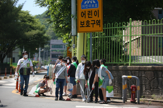 지난달 19일 경남 창원시 마산회원구 한 어린이보호구역에서 어린이들이 담배꽁초 줍기 활동을 하는 모습.   초록우산어린이재단 제공