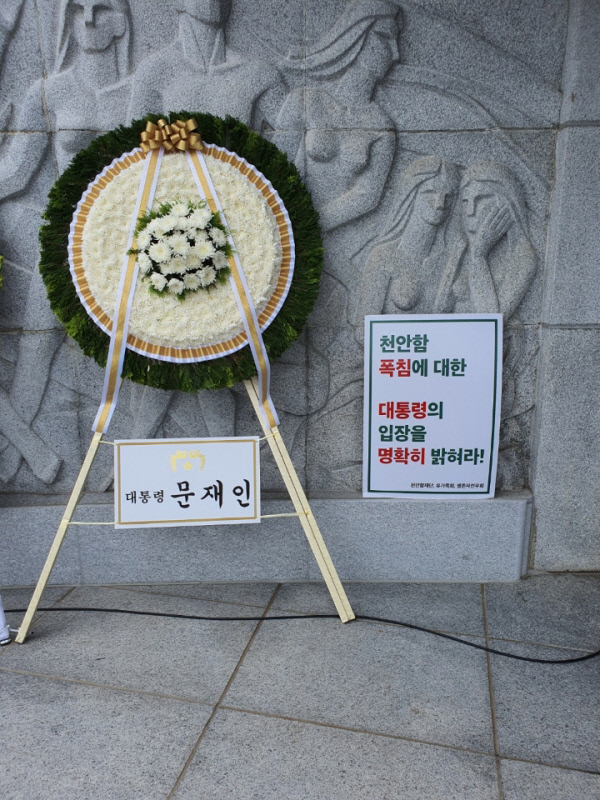 6일 국립서울현충원 현충탑 앞에 놓인 문재인 대통령 조화 옆에 천안함 생존 장병들이 이날 시위에 사용한 피켓을 놓은 모습. 피켓에는 “천안함 폭침에 대한 대통령의 입장을 명확히 밝혀라”라는 내용이 적혀 있다. 최원일 전 천안함 함장 제공