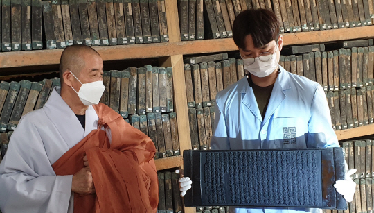 해인사 주지 현응 스님이 한 대장경 연구원이 들고 있는 ‘광명경’판에 대해 설명하고 있다.