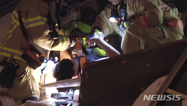 [서프사이드=AP/뉴시스]24일(현지시간) 미 플로리다주 마이애미데이드 카운티 서프사이드에서 12층짜리 챔플레인 타워 사우스 아파트가 무너져 구조대가 구조한 생존자와 주먹 인사를 하고 있다. 이날 새벽에 건물 일부가 무너져 아파트 136가구 중 55가구가 붕괴됐다.