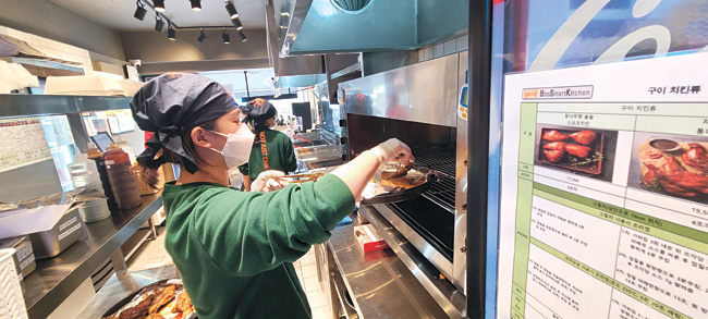한 비비큐치킨 매장에서 직원이 소스를 바른 치킨을 오븐에 넣고 있다.   제네시스 비비큐 제공