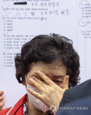 (서울=연합뉴스)  7일 서울대학교 행정관 앞에서 열린‘서울대학교 청소 노동자 조합원 사망 관련 서울대학교 오세정 총장 규탄 기자회견’에서 민주노총 조합원이 청소 노동자가 본 시험지 손 피켓 앞에 서 눈물을 닦고 있다. 2021.7.7