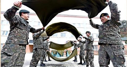 육군 전방부대 장병들이 겨우내 묵은 먼지를 털어내기 위해 봄 햇살 속에 모포를 터는 모습. 육군과 해병대가 모포 대신 솜이불로 대체하기로 함에 따라 ‘추억의 병영 모포털기’는 70년 만에 역사속으로 사라질 것으로 보인다. 국방일보 제공