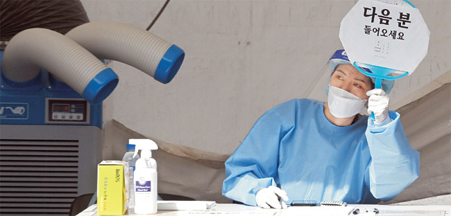 1615명의 사상 최대 코로나19 신규 확진자가 발생한 14일 오전 서울 양천구 코로나19 임시선별검사소에서 의료진이 냉풍기로 폭염을 식히며 ‘다음 분 들어오세요’라고 적힌 팻말을 들고 있다.  김선규 기자