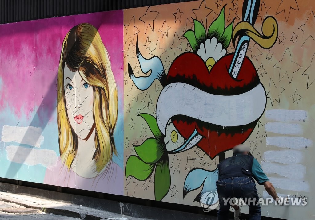 (서울=연합뉴스) 서울 종로구의 한 서점 외벽에 그려진 대권 주자 윤석열 예비후보의 부인 김건희 씨를 비방하는 내용의 벽화가 논란이 되고 있는 가운데 30일 오전 한 건물 관계자가 벽화의 글자를 흰색 페인트로 지우고 있다.