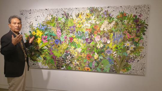 정우범 작가가 ‘판타지아’ 연작 중 대형 작품(250×124㎝) 앞에서 “코로나 시기의 우울하고 답답한 마음을 오방색 꽃밭의 아름다움으로 위로받으셨으면 좋겠다”고 했다.