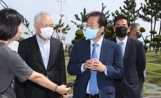 드라마 ‘모래시계’의 검사 모델로 알려진 국민의힘 대선주자인 홍준표(왼쪽 세 번째) 의원이 6일 오전 강원 강릉 모래시계 공원에서 기자들의 질문에 답변하고 있다.  뉴시스