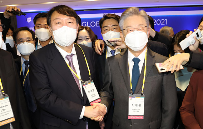 이재명(오른쪽) 더불어민주당 대선 후보와 윤석열(왼쪽) 국민의힘 대선 후보가 10일 오전 서울 광장동 그랜드워커힐호텔에서 열린 한 언론사 주최 포럼에서 양당 후보 결정 후 처음으로 만나 악수를 하고 있다.  국회사진기자단