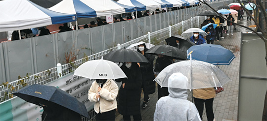 코로나19 위중증 환자가 661명으로 역대 최대를 기록한 30일 오전 서울 강서구 마곡동 선별진료소에 시민들이 코로나19 진단검사를 받기 위해 우산을 쓰고 길게 줄을 서서 차례를 기다리고 있다.