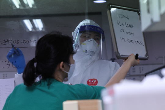 7일 위중증 환자가 774명으로 또 최다를 기록하는 등 병상 부족 사태가 장기화하고 있는 가운데 6일 경기 평택 박애병원에서 의료진이 음압병동 유리벽을 사이에 두고 의사소통을 하고 있다. 전날 오후 5시 기준 수도권의 코로나19 중증환자 전담 병상 가동률은 83.6%를 기록했다. 연합뉴스