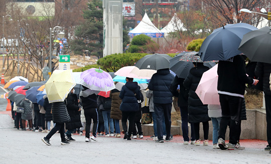 코로나19 확진자가 폭증하면서 접촉에 따른 검사대상자들도 급증하고 있는 가운데 10일 오전 대전 서구 둔산동 대전시청 앞에 설치된 코로나19 선별진료소에 검사를 받으려는 시민들이 우산을 들고 차례를 기다리고 있다. 연합뉴스