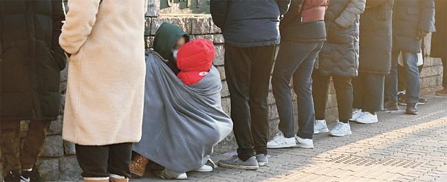 17일 오전 한 엄마가 아이와 함께 담요를 두르고 체감온도 영하 10도의 추위와 코로나19 감염 불안에 떨면서 서울 강서구 염창동 강서보건소 선별진료소 앞에 길게 늘어선 대기자들 사이에 웅크리고 앉아 진단검사 순서를 기다리고 있다. 신창섭 기자