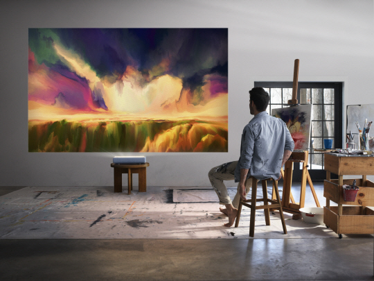 삼성전자는 프리미엄 가정용 프로젝터 ‘더 프리미어(The Premiere)’가 북미 고급 프로젝터 시장에서 올해 누적 점유율 기준으로 1위에 올라섰다고 17일 밝혔다. 사진은 삼성전자 모델이 더 프리미어로 영상을 관람하고 있는 모습.  삼성전자 제공