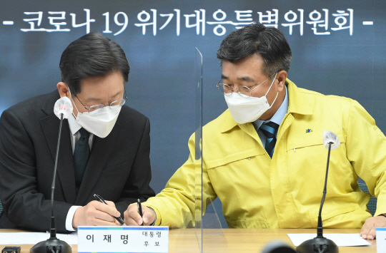 이재명(왼쪽) 더불어민주당 대선 후보와 윤호중 원내대표가 17일 오전 서울 여의도 당사에서 열린 코로나19 위기대응 특별위원회 회의에서 필담을 하고 있다. 국회사진기자단