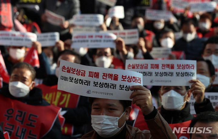 [서울=뉴시스] 지난 8일 오후 서울 영등포구 국회의사당역 인근에서 열린 코로나19 피해 실질 보상 촉구 정부·여당 규탄대회에서 참석자들이 구호를 외치고 있다. 2021.12.08.