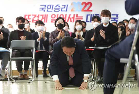 (서울=연합뉴스) 국민의힘 윤석열 대선 후보가 1일 오후 서울 여의도 대하빌딩에서 열린 선대위 신년인사회에서 구두를 벗고 국민들에게 큰절을 하고 있다. 2022.1.1 [공동취재]