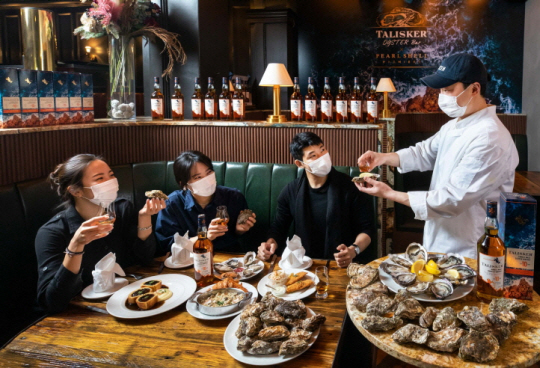 코로나19 이후 여러 위스키를 경험하고 자신만의 취향을 찾으려는 새로운 음주문화가 떠오르면서 주류업체들도 ‘즐길 수 있는 위스키’를 테마로 다양한 마케팅에 나서고 있다. 국내 1위 위스키 업체 디아지오코리아가 프리미엄 오이스터 바 ‘펄쉘 프리미에’와 진행 중인 싱글몰트 스카치위스키 탈리스커와 굴 요리 푸드 페어링 프로모션에 참가한 이들이 세프의 설명을 듣고 있는 모습.   디아지오코리아 제공