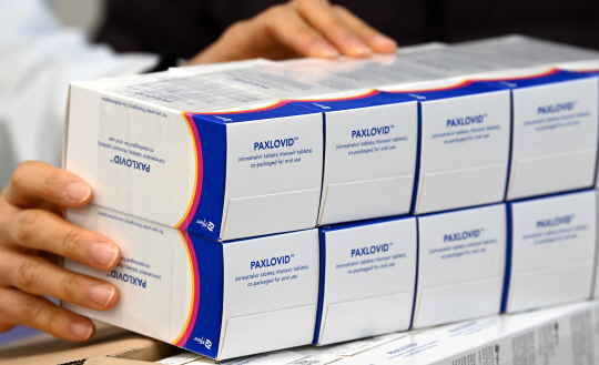 먹는 코로나19 치료제 ‘팍스로비드’ 처방 및 투약이 시작된 14일 오전 서울 금천구의 한 약국에서 약사가 충북 청주 물류창고센터에서 배송된 치료제를 건네받고 있다. 작은 흰 박스 하나에 5일치 분량 30알이 들어 있다.  곽성호 기자