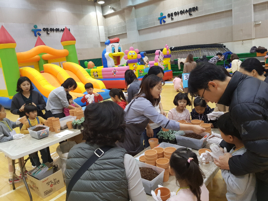 2019년 11월 경기 화성시 병점동 유앤아이센터 강당에서 열린 ‘가족품앗이 놀이한마당’에서 공동 육아를 하는 부모와 자녀들이 화분에 관상용 식물을 심는 체험을 하고 있다. 화성시청 제공