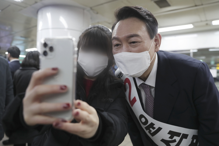 [서울=뉴시스] 윤석열 국민의힘 대선 후보가 17일 저녁 서울 을지로입구역에서 퇴근하는 시민과 셀카를 찍고 있다. (사진=국민의힘 제공) 2022.01.17.  *재판매 및 DB 금지