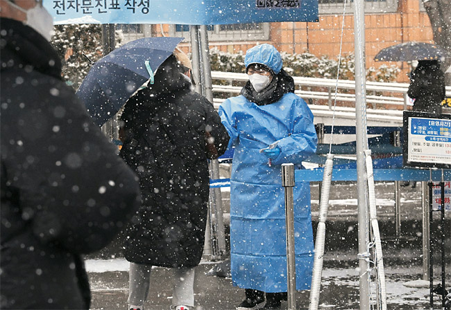 오미크론 변이 확산으로 신규 확진자가 5805명 발생한 19일 오전 영등포구보건소 의료진이 당산동 선별진료소에서 함박눈을 맞으며 코로나19 검사를 받으러 온 주민들을 안내하고 있다.  신창섭 기자