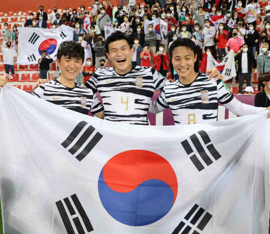 황인범(왼쪽부터)과 김민재, 백승호가 2일(한국시간) UAE 두바이의 라시드 스타디움에서 카타르월드컵 본선 진출을 확정한 직후 활짝 웃으며 태극기 세리머니를 펼치고 있다.  연합뉴스