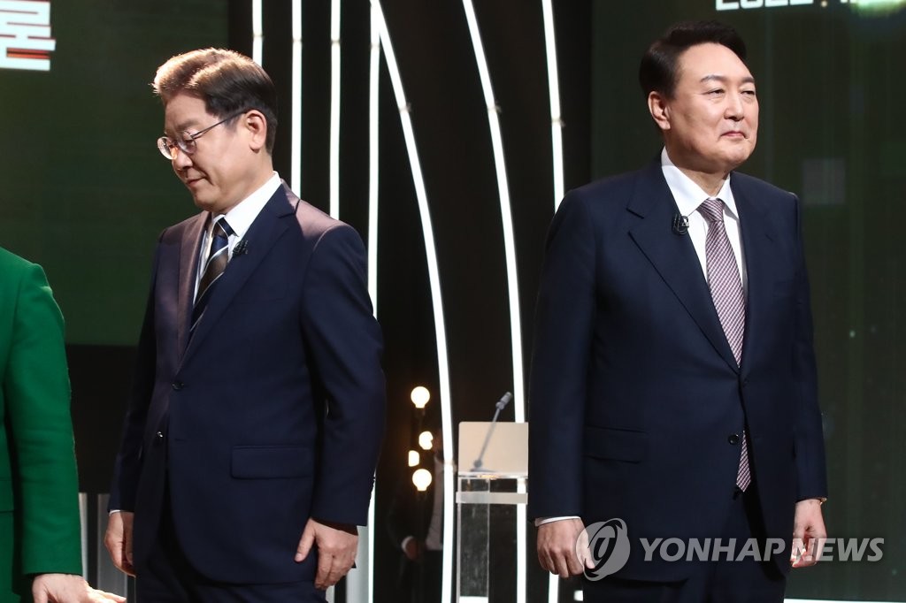 (서울=연합뉴스) 3일 오후 서울 여의도 KBS 공개홀에서 열린 방송 3사 합동 초청 ‘2022 대선후보 토론’에서 더불어민주당 이재명 대선 후보(왼쪽)가 기념촬영을 마친 뒤 자리로 돌아가고 있다. 오른쪽은 국민의힘 윤석열 대선 후보. 2022.2.3 [국회사진기자단]