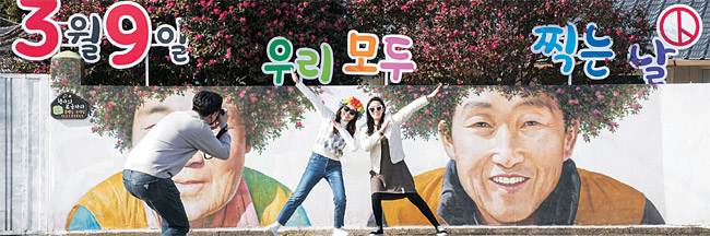 13일 전남 신안군 암태도 기동삼거리 벽화 앞에서 대선투표독려 홍보물을 배경으로 관광객들이 기념촬영을 하고 있다.  연합뉴스
