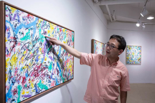 지창림 화백이 작품 ‘누드 풍경’을 가리키며 “꽃들 사이에 있는 인체 누드의 다양한 이미지를 표현했다”고 설명했다. 스페이스 오롯이 제공