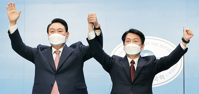 윤석열(왼쪽) 국민의힘 대선 후보와 안철수 국민의당 대선 후보가 3일 오전 국회 소통관에서 윤 후보로 단일화하는 기자 회견을 한 뒤 손을 잡고 두 팔을 들어 보이고 있다.   국회사진기자단