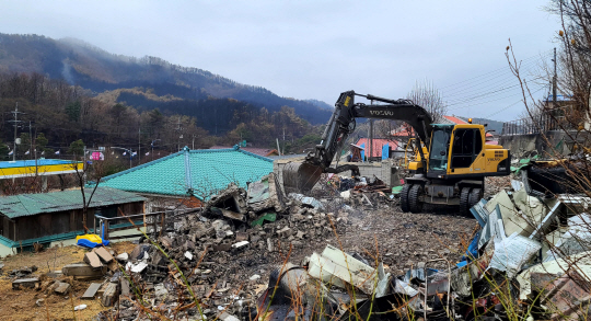강원 동해시 산불 피해 지역 주민들이 13일 빗속에서 화마에 소실된 주택을 굴착기를 동원해 정리하는 등 복구작업을 벌이고 있다.  연합뉴스