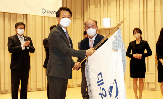 정창선(오른쪽) 중흥그룹 회장이 백정완 대우건설 신임 사장에게 사기를 전달하고 있다.    대우건설 제공