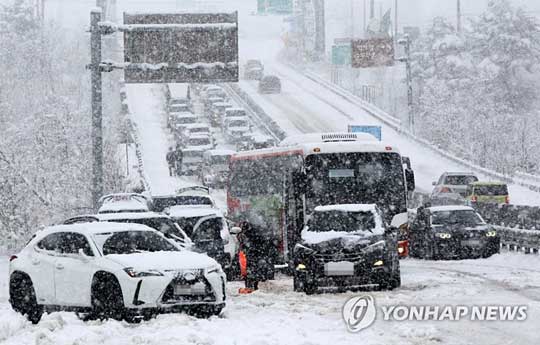 (속초=연합뉴스) 봄을 시샘하는 폭설이 쏟아진 19일 미시령동서관통도로 일부 구간에서 차들이 체증을 빚고 있다.2022.3.19