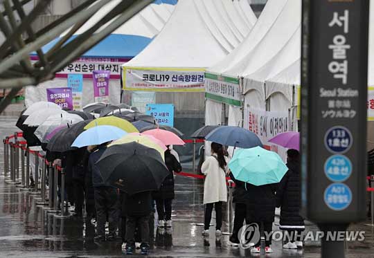 (서울=연합뉴스) 주말인 19일 비가 내리는 가운데 서울 중구 서울역 임시 선별검사소에서 우산을 쓴 시민들이 검사를 기다리고 있다. 2022.3.19