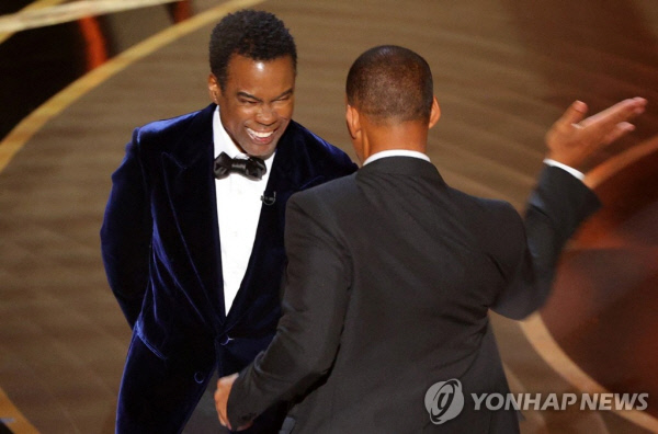 배우 윌 스미스(오른쪽)가 27일 미국 로스앤젤레스 할리우드 돌비극장에서 열린 제94회 오스카 시상식에서 배우 겸 코미디언 크리스 록의 뺨을 때리려 하고 있다. 이날 장편 다큐멘터리상 시상자로 나선 록은 스미스의 아내 제이다 핑킷의 삭발한 헤어스타일을 소재로 농담했는데, 이에 격분한 스미스가 무대로 난입해 록의 안면을 가격했다. (연합뉴스 자료사진)