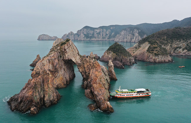 ‘홍도 10경’ 중 제1경으로 꼽히는 남문 바위와 홍도 유람선.
