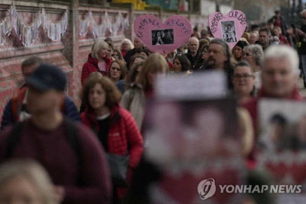 영국 런던에 있는 코로나19 희생자 추모 벽 앞을 사람들이 지나가고 있다. AP 연합뉴스