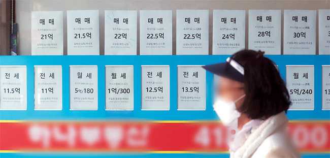 집값 상승·하락 요인이 팽팽히 맞서면서 서울 아파트 매매 거래량이 급감한 가운데 2일 서울의 한 부동산 업체에 빼곡히 내걸린 거래 광고물 앞을 한 시민이 지나가고 있다. 뉴시스