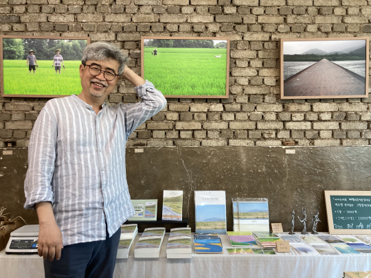 지난 4일 곡성 생태책방 ‘들녘의 마음’에서 만난 김탁환 소설가가 환하게 웃고 있다. 책방 벽에는 벼가 무럭무럭 자라는 논에서 이동현 미실란 대표와 찍은 사진들이 걸려 있다.