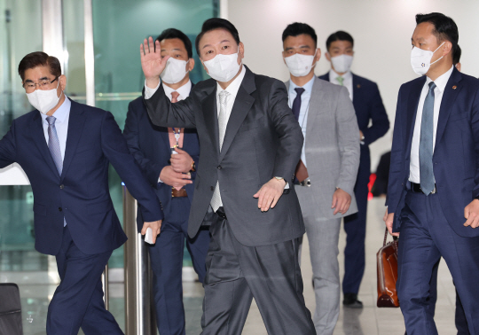 윤석열 대통령이 12일 오전 서울 용산 대통령실 청사로 출근하면서 질문을 하기 위해 기다리고 있는 취재진에게 손을 흔들고 있다.  연합뉴스